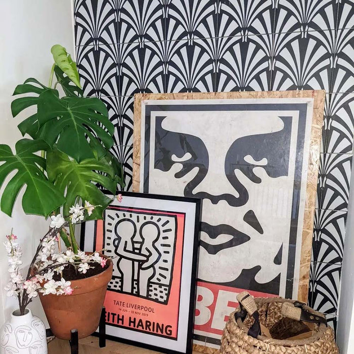 Alhambra Casa 20x20cm Moroccan tiles styled in an artistic setting with framed modern art prints, greenery, and natural textures, highlighting the tile’s bold black and white fan pattern for a creative, contemporary interior look.