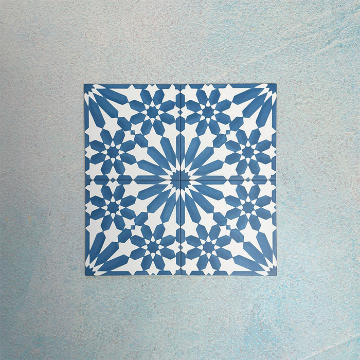 Arrangement of Fizaan Azure Blue 20x20cm Moroccan-style porcelain tiles, showcasing a repeating geometric pattern in vibrant blue and white tones.