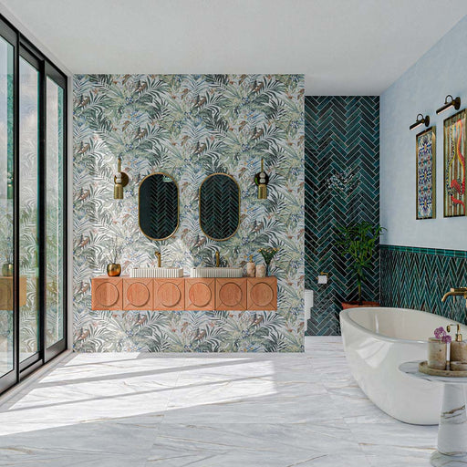 Bathroom featuring Barbados 60cm x 120cm patterned wall tiles with a tropical botanical design, paired with green herringbone tiles, marble-effect flooring, a floating vanity, freestanding bath and brass fixtures.
