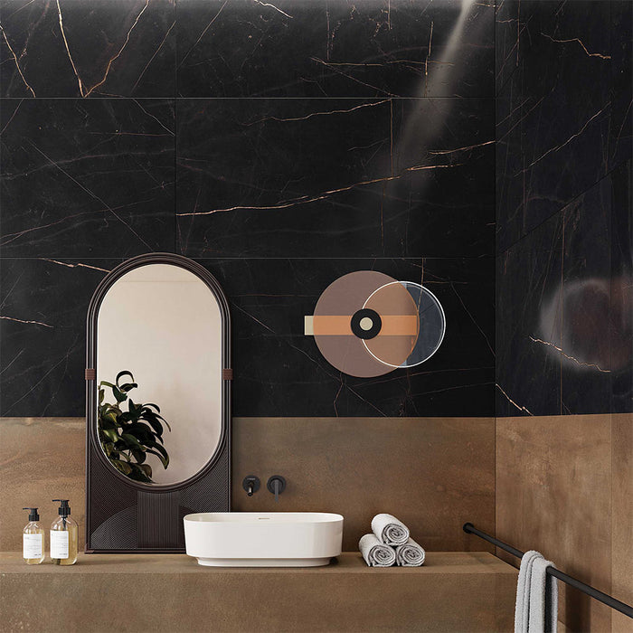 Bathroom interior featuring Bassano Precious Noir Lux 3D 60 × 120cm marble-effect wall and floor tiles, styled with warm bronze tones, contemporary black fittings, sculptural mirror, and elegant gold veining throughout.