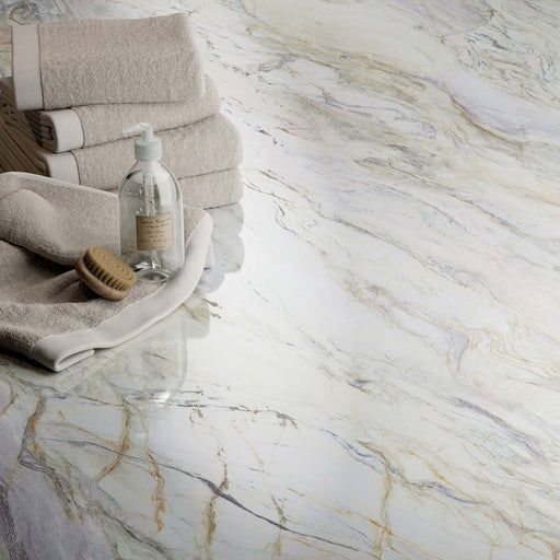 Close-up of Bassano Quartz Lux 3D 60 × 120cm marble-effect wall and floor tiles, showcasing soft white tones with flowing gold and grey veining and a luxurious polished contemporary finish.