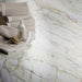 Close-up of Bassano Quartz Lux 3D 60 × 120cm marble-effect wall and floor tiles, showcasing soft white tones with flowing gold and grey veining and a luxurious polished contemporary finish.