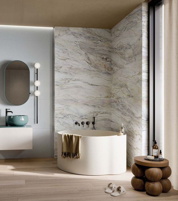 Luxury bathroom featuring Bassano Quartz Lux 3D 60 × 120cm marble-effect wall and floor tiles, paired with a freestanding bath, soft neutral tones, warm wood flooring, and contemporary black fittings.