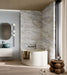 Luxury bathroom featuring Bassano Quartz Lux 3D 60 × 120cm marble-effect wall and floor tiles, paired with a freestanding bath, soft neutral tones, warm wood flooring, and contemporary black fittings.
