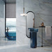 Bathroom interior featuring Bassano River Blue Lux 3D 60 × 120cm marble-effect wall and floor tiles, styled with soft blue veining, a translucent blue basin and bathtub, black fittings, and contemporary lighting for a calm, luxurious atmosphere.