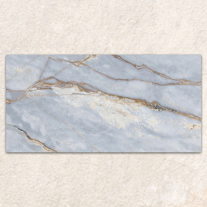 Single tile display of Bassano River Blue Lux 3D 60 × 120cm marble-effect wall and floor tiles, featuring soft blue tones, flowing gold and beige veining, and a polished finish inspired by luxurious natural stone.