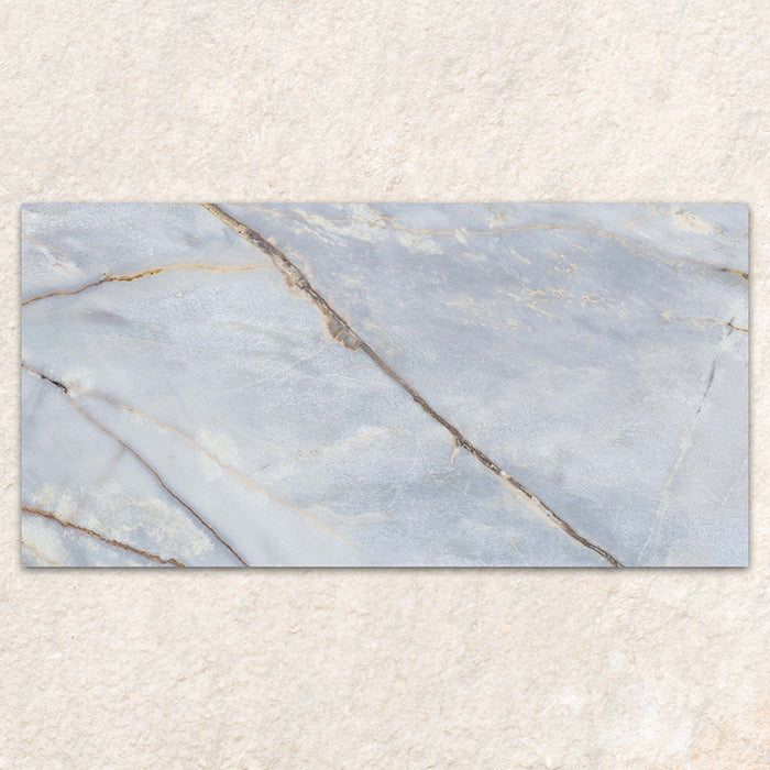 Single tile display of Bassano River Blue Lux 3D 60 × 120cm marble-effect wall and floor tiles, featuring soft blue tones, flowing gold and beige veining, and a polished finish inspired by luxurious natural stone.
