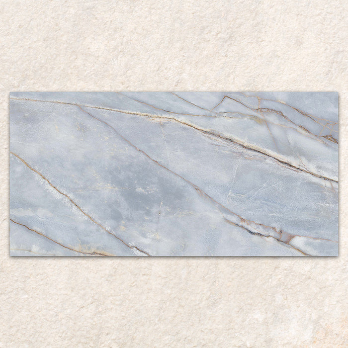 Single tile display of Bassano River Blue Matt 60 × 120cm marble-effect wall and floor tiles, featuring soft blue tones, flowing gold and beige veining, and a smooth matt finish inspired by elegant natural stone.