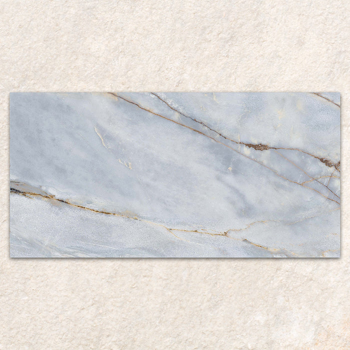 Single tile display of Bassano River Blue Matt 60 × 120cm marble-effect wall and floor tiles, featuring soft blue tones, flowing gold and beige veining, and a smooth matt finish inspired by elegant natural stone.
