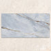 Single tile display of Bassano River Blue Matt 60 × 120cm marble-effect wall and floor tiles, featuring soft blue tones, flowing gold and beige veining, and a smooth matt finish inspired by elegant natural stone.