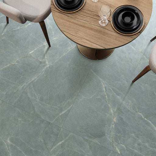 Dining area featuring Bassano Sea Green Natural Matt 60 × 120cm marble-effect wall and floor tiles, styled with soft green tones, natural wood furniture, and contemporary neutral seating for a calm modern interior.