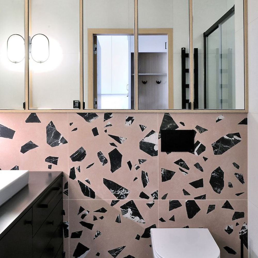 Bathroom vanity wall featuring Chunks ROCK Terrazzo Pink 60x60cm porcelain tiles in a terrazzo effect with bold black marble-style fragments on a soft pink base, creating a contemporary statement bathroom wall design.