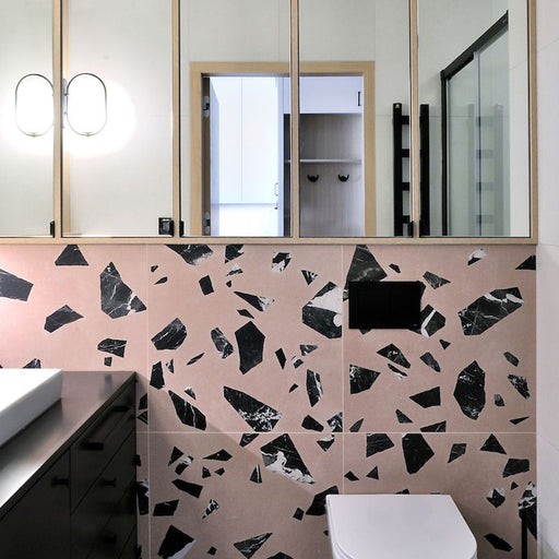 Bathroom vanity wall featuring Chunks ROCK Terrazzo Pink 60x60cm porcelain tiles in a terrazzo effect with bold black marble-style fragments on a soft pink base, creating a contemporary statement bathroom wall design.