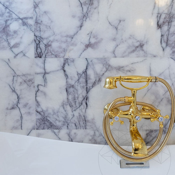 Bathroom interior featuring Fitzrovia Lilac 30.5 x 61cm honed natural marble tiles across walls and floor, showcasing soft lilac veining against a light base, styled with a freestanding bath, brushed brass fittings, and a bright, refined setting.