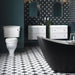 Bathroom setting featuring Pole Star Black Moroccan-style 25x25cm patterned porcelain floor tiles, creating a bold geometric look beneath twin white vanity units and dark cabinetry.