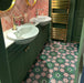 Bathroom featuring Fizaan Autumn Moroccan-style 20×20cm porcelain floor tiles, showcasing a green and pink geometric floral pattern paired with dark green cabinetry and brass fittings.