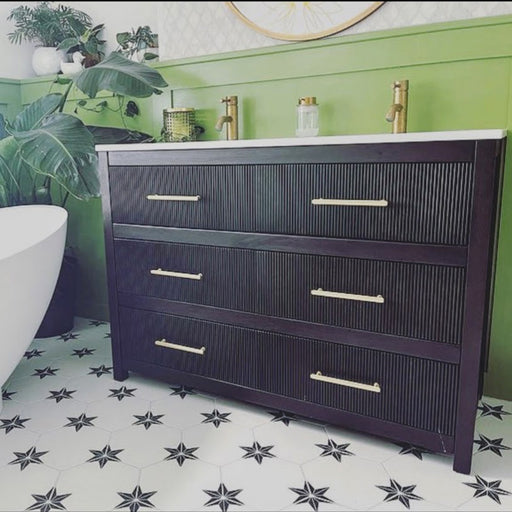 Bathroom setting featuring Pole Star Black Moroccan-style 22x25cm hexagon patterned porcelain floor tiles, paired with a dark wood vanity, brass fittings, and green wall panelling.