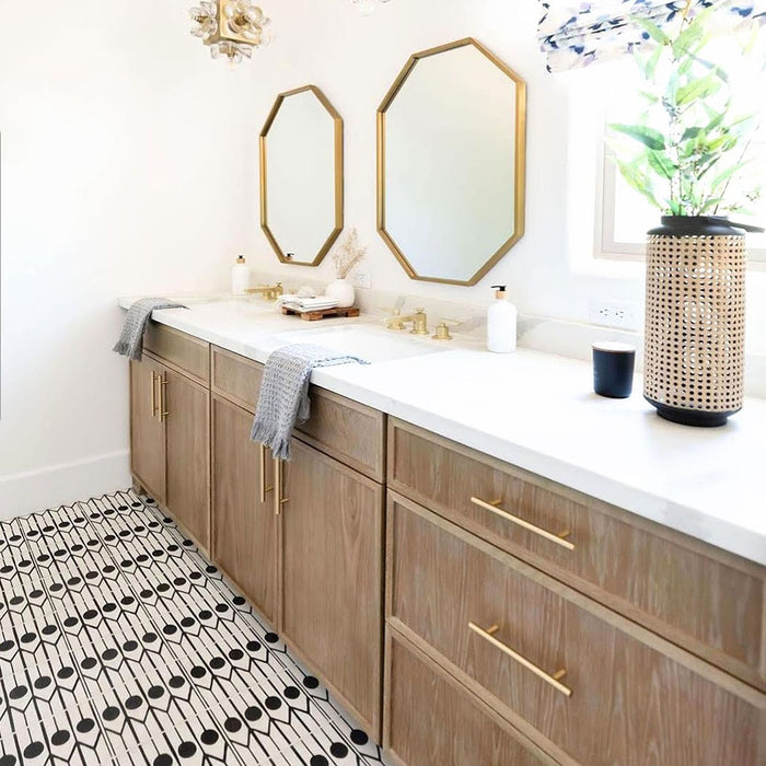 Alhambra Felisa 20x20cm Moroccan tiles used as bathroom flooring, showcasing a bold black and white pattern paired with light wood cabinetry, gold fixtures, and white countertops for a modern Moroccan-inspired aesthetic.