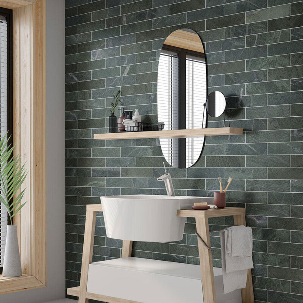 Bathroom interior featuring Fitzrovia Verde 5 x 20cm honed natural marble tiles, installed in a horizontal brick layout to create a rich, textured backdrop, showcasing deep green tones with natural veining, paired with light wood finishes and soft neutral elements for a calm, design-led space.