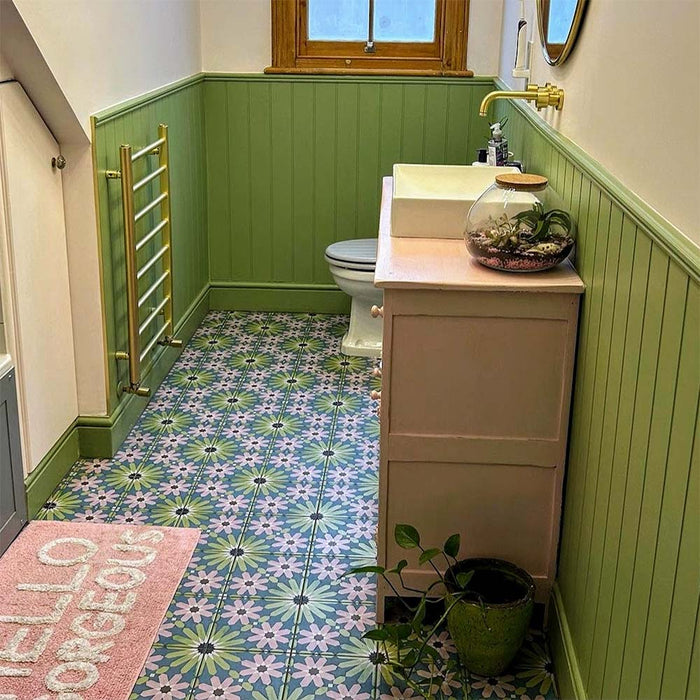 Bathroom featuring Fizaan Summer Moroccan-style 20×20cm porcelain floor tiles, showcasing a blue, green and pink geometric pattern paired with green panelling and brass fittings.