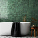Zellij Gloss Green square Moroccan style tiles, 13.2cm x 13.2cm, deep green tones with natural tonal variation, glossy glazed finish, handmade-look surface, square format used on bathroom walls behind a freestanding bath.