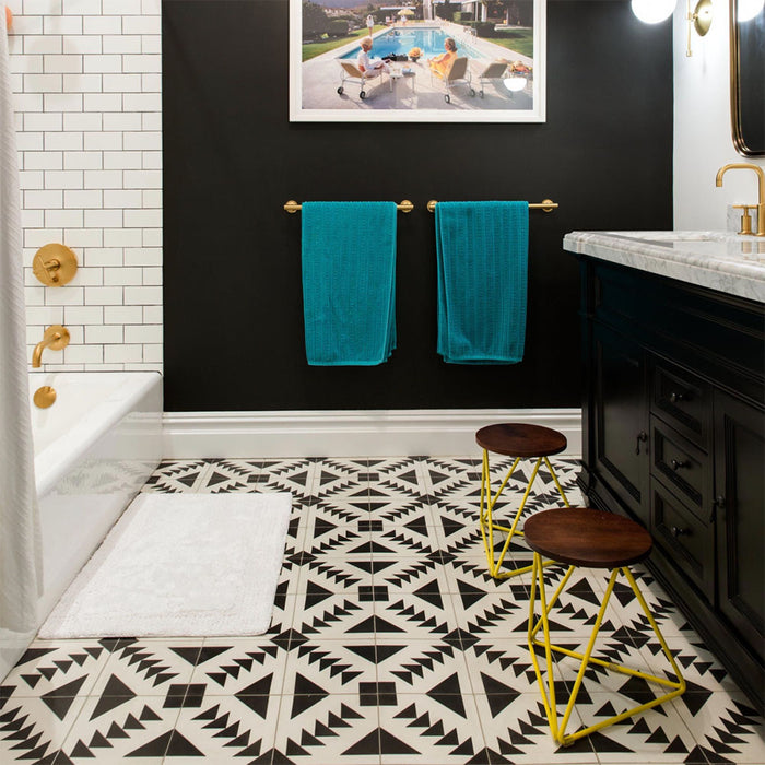 Alhambra Alkazar 20x20cm Moroccan tiles featured in a modern bathroom, showcasing bold black and white geometric patterns that create a striking contrast against black walls, brass fixtures, and white subway tiles.