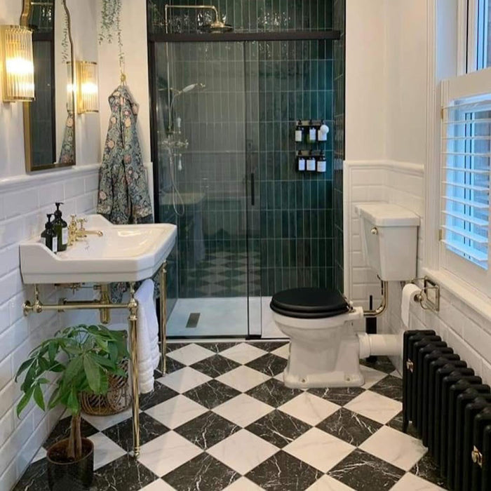 Bathroom interior featuring Fitzrovia White 15.2x15.2cm honed natural marble tiles paired with black marble in a classic chequerboard floor, styled with green wall tiles, brass fixtures, and a traditional sink.