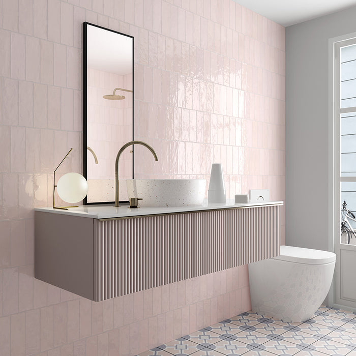 Zellij Pink Mist brick tile in a 6.5cm x 20cm format, Moroccan style, soft blush pink tones with subtle tonal variation, glossy glazed finish, shown in a contemporary bathroom wall setting with a floating vanity and modern fittings.
