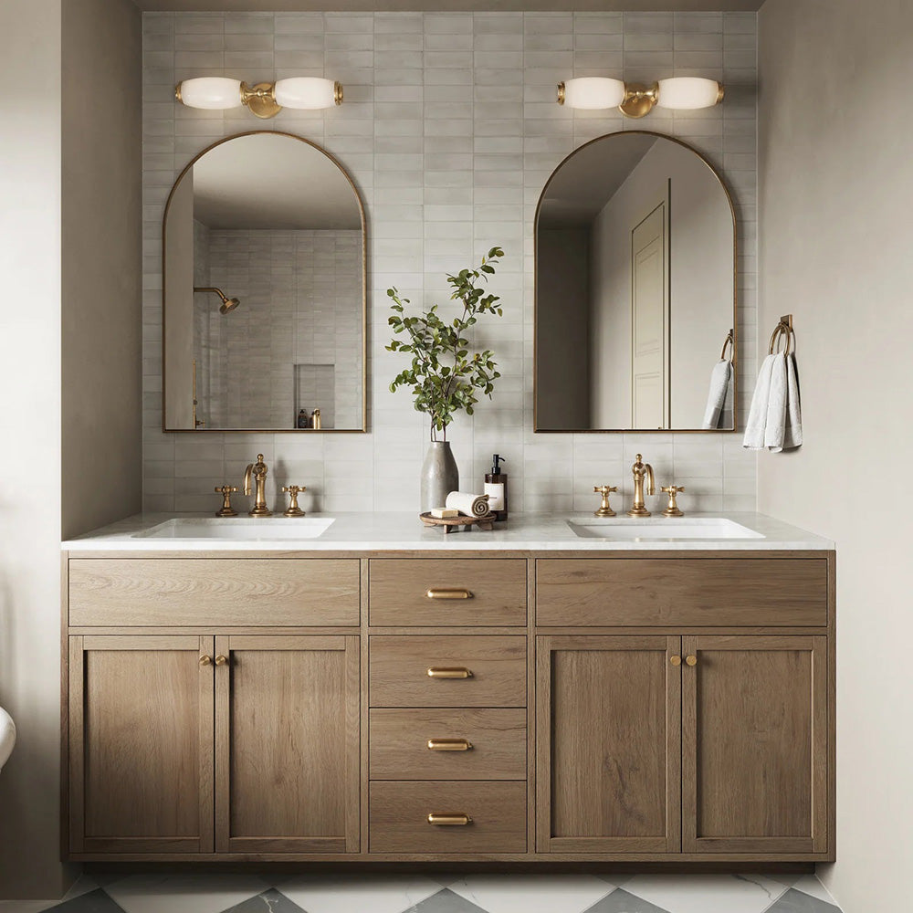 Bathroom setting featuring Atlas White Mini Brick 5x15cm matt wall tiles, laid in a horizontal brick format to create a soft, textured backdrop. The subtle tonal variation and refined matt finish bring a calm, understated feel, paired with warm wood cabinetry, brass fittings, and arched mirrors for a balanced, contemporary look.