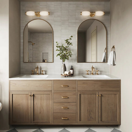 Bathroom setting featuring Atlas White Mini Brick 5x15cm matt wall tiles, laid in a horizontal brick format to create a soft, textured backdrop. The subtle tonal variation and refined matt finish bring a calm, understated feel, paired with warm wood cabinetry, brass fittings, and arched mirrors for a balanced, contemporary look.