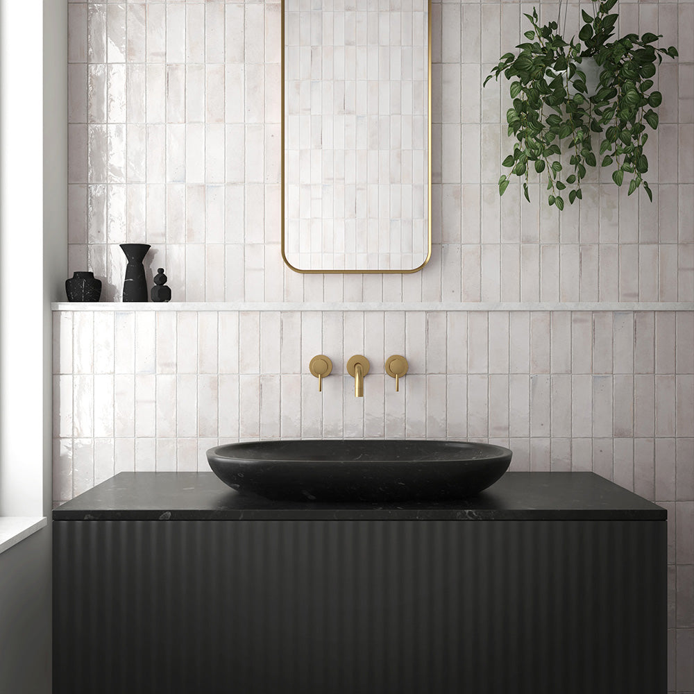 Bathroom interior featuring Beijing White 5.1x16.1cm Moroccan brick tiles laid vertically on the wall, paired with brushed brass fixtures, a black countertop basin, and a gold-framed mirror for a modern minimalist look.
