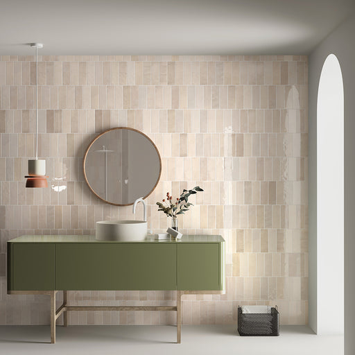 Bathroom setting featuring Zellij Bone Brick Moroccan-style tiles in a 6.5cm x 20cm format, with a soft warm beige tone and subtle handmade texture, styled with a green vanity unit, round mirror, and contemporary basin for a calm, modern look.