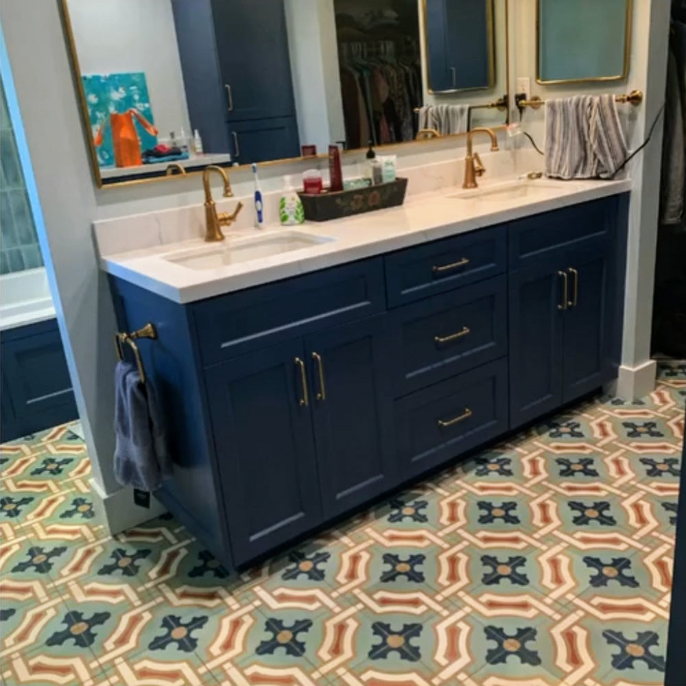 Bathroom interior featuring Europa Cologne 20x20cm Victorian Moroccan style floor tiles in blue, green and warm beige tones, styled with a navy vanity unit, brass taps and large mirrors.