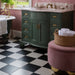 Bathroom featuring Chessboard White 25×25cm Victorian-style porcelain floor tiles paired with black tiles in a classic chequerboard pattern, styled with a green vanity unit, pink wall tiles, brass fixtures, and a freestanding bath for a vintage-inspired look.