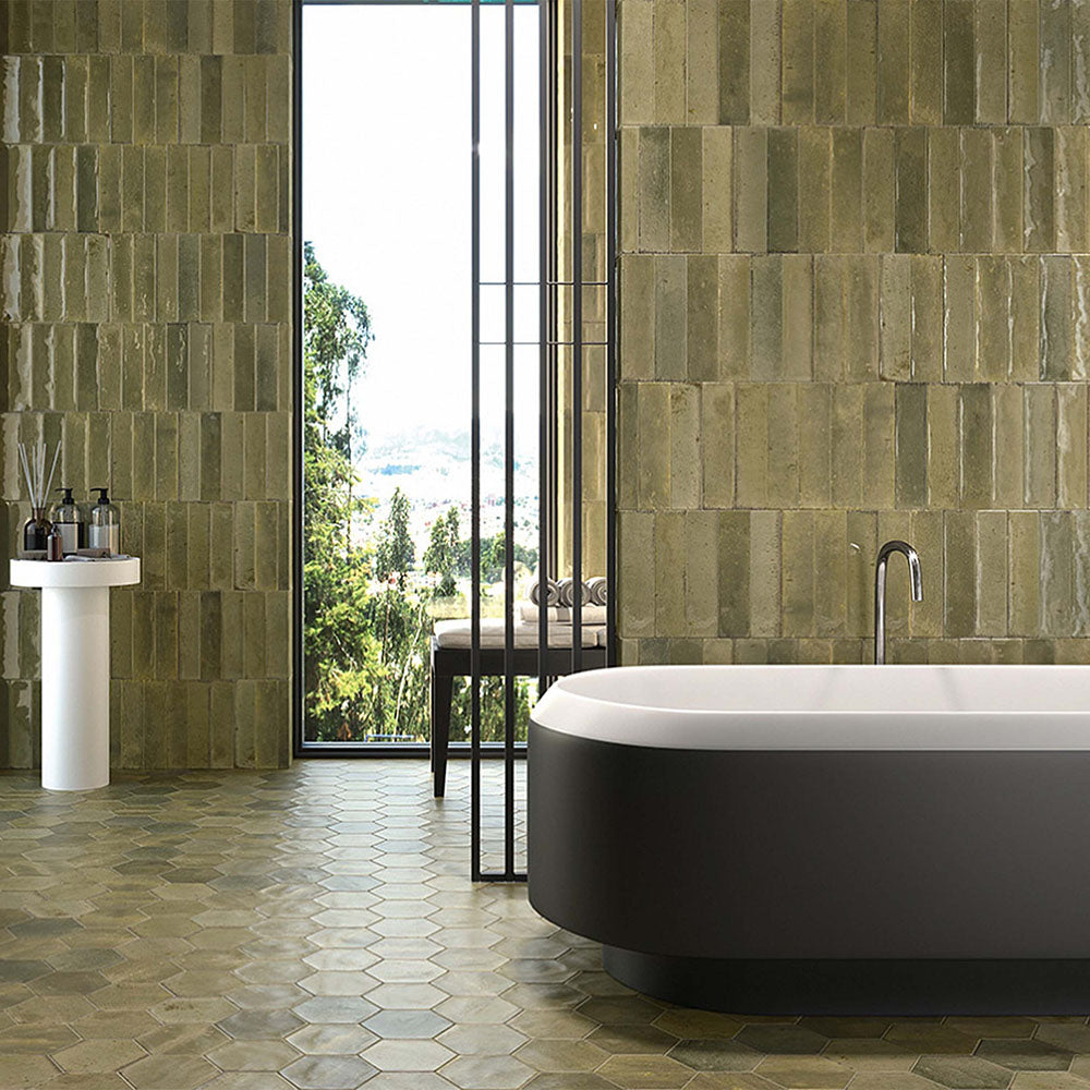 Contemporary bathroom featuring Izmir Brick Sage Green Gloss 6x25cm ceramic wall tiles, styled with a freestanding black-and-white bath, hexagonal floor tiles, and large window views bringing in natural light.