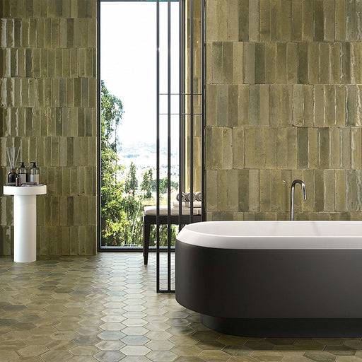 Contemporary bathroom featuring Izmir Brick Sage Green Gloss 6x25cm ceramic wall tiles, styled with a freestanding black-and-white bath, hexagonal floor tiles, and large window views bringing in natural light.