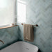 Zellij Aqua Blue brick tiles, 6.5cm x 20cm, Moroccan style, soft aqua blue tones with natural shade variation, glossy glazed finish, laid in a herringbone pattern, creating a calm and contemporary bathroom bath setting.