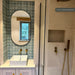Bathroom featuring Bedouin Tetuan Green 15x15cm Moroccan-style patterned wall tiles, styled as a vanity feature wall with a contemporary basin, brushed brass fixtures, neutral stone-effect tiles and a walk-in shower.