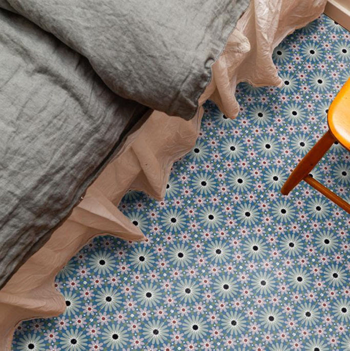 Bedroom floor featuring Fizaan Artisan Mini Moroccan-style 15×15cm porcelain tiles, showcasing a blue, green and soft pink geometric pattern styled with neutral bedding and wooden furniture.