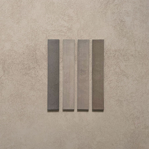 Close-up of Belem Grey 5cm x 30cm artisanal porcelain wall tiles, displaying four slim brick tiles with varied grey and taupe tones, subtle texture and gentle tonal variation.