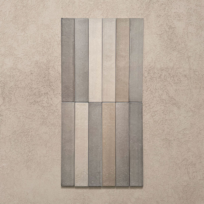 Close-up of Belem Grey 5cm x 30cm artisanal porcelain wall tiles, showcasing the slim brick format, soft grey and taupe tones, subtle surface texture and natural-looking tonal variation.