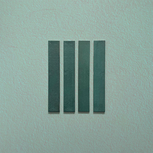 Close-up of Belem Verde Green 5cm x 30cm artisanal porcelain wall tiles, displaying four slim brick tiles with deep green tones, subtle surface texture and gentle tonal variation.