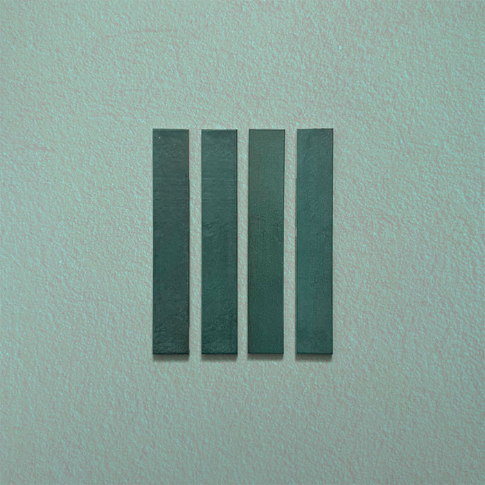 Close-up of Belem Verde Green 5cm x 30cm artisanal porcelain wall tiles, displaying four slim brick tiles with deep green tones, subtle surface texture and gentle tonal variation.