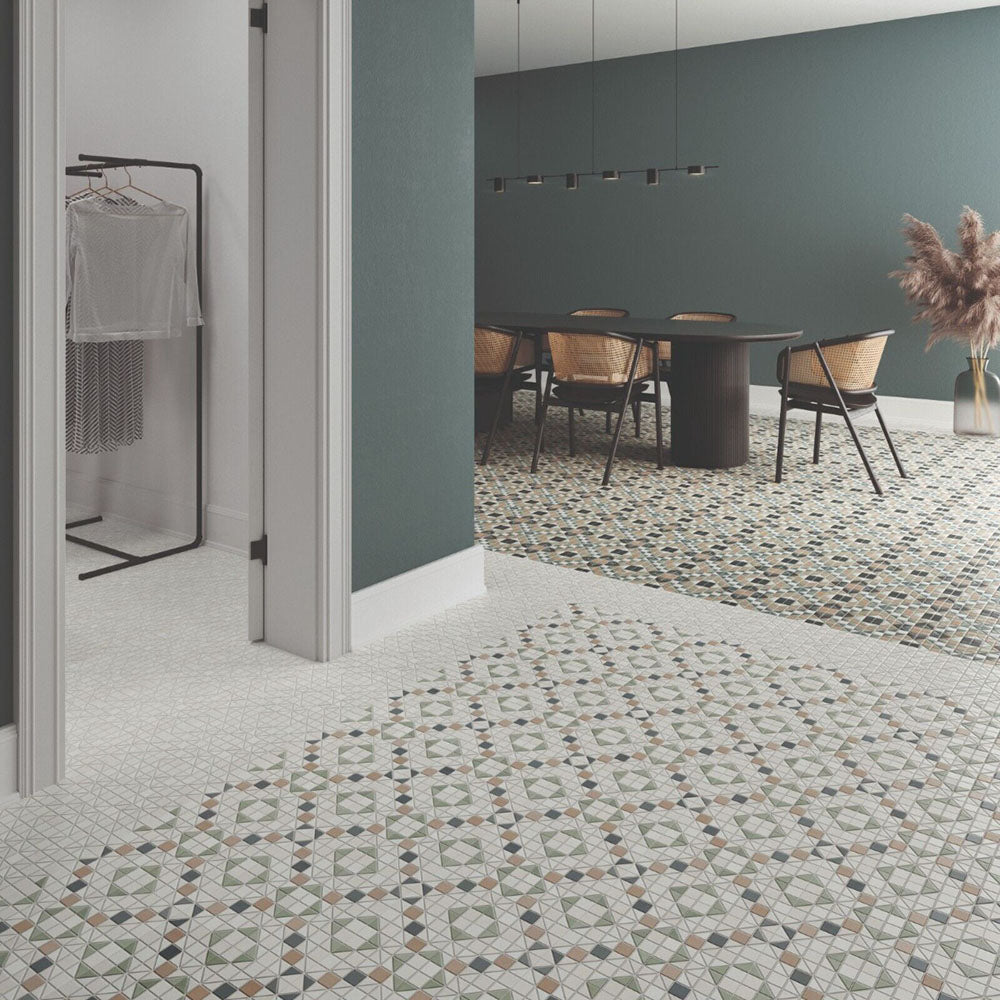 Dining area featuring Belgravia Marina Mosaic 28 × 28cm Victorian style patterned floor tiles, with intricate geometric detailing in soft green and neutral tones, paired with dark wood table, woven chairs, and muted green walls.