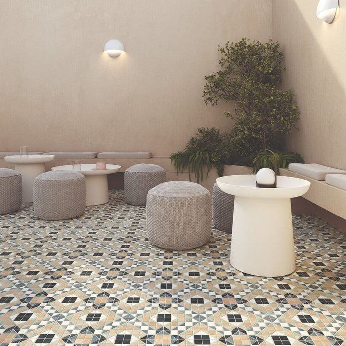 Outdoor seating area featuring Belgravia Marina Plus Mosaic 28 × 28cm Victorian style patterned floor tiles, with intricate geometric detailing in soft blue, green and beige tones, paired with neutral seating, textured pouffes, and warm-toned walls.