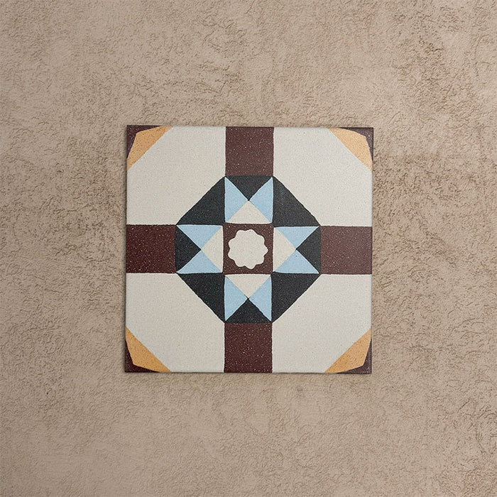 Single Europa Berlin 20x20cm Victorian Moroccan style tile displayed against a textured beige background, featuring a geometric star pattern in burgundy, blue, mustard and cream tones in a close-up product setting.