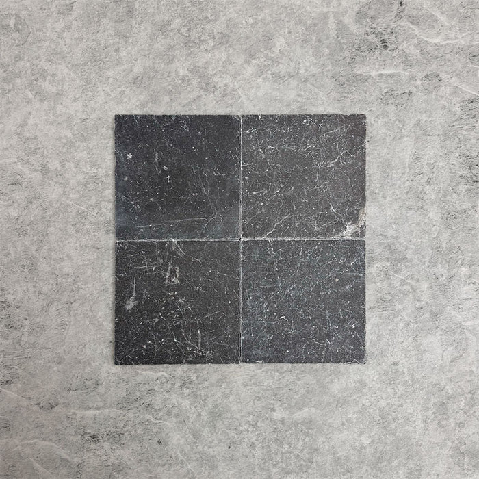 Fitzrovia Black 15.2x15.2cm tumbled natural marble tiles arranged in a square layout, showcasing deep charcoal tones, natural veining, tonal variation, and a softly aged, textured finish.