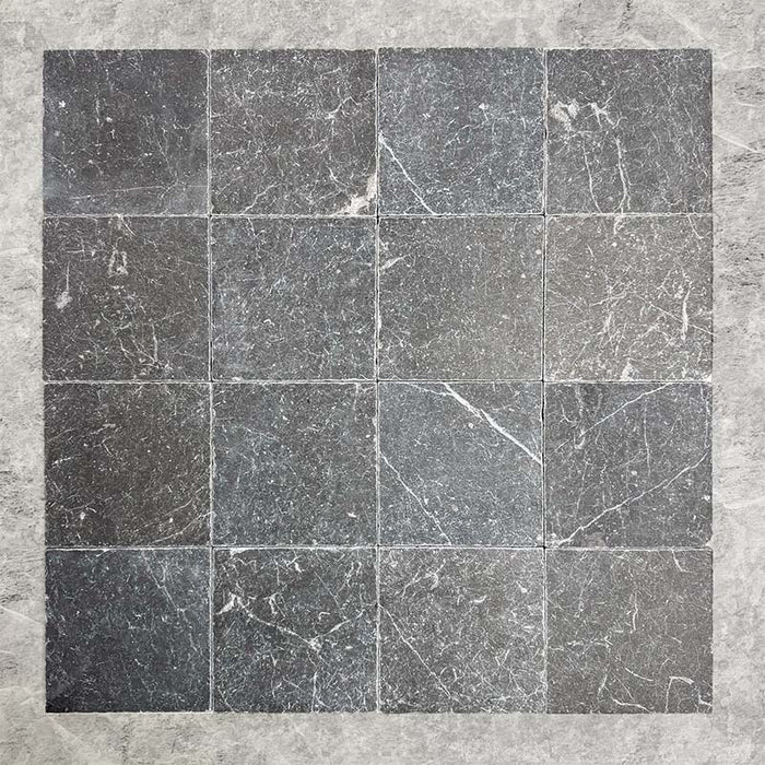 Group of Fitzrovia Black 15.2x15.2cm tumbled natural marble tiles arranged in a square layout, showcasing deep charcoal tones, natural veining, tonal variation, and a softly aged, textured finish.