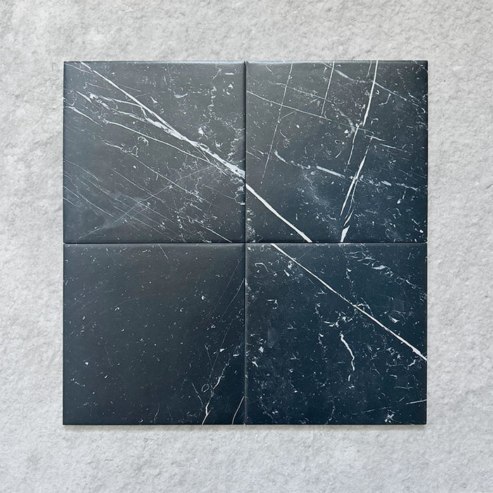 Four Calacatta Nero Black marble-effect 25×25cm porcelain tiles showing natural white veining variation on a deep black base, ideal for creating a bold, authentic marble look across floors and walls.