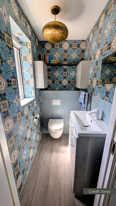Bathroom featuring Bloom Azul Blue 20x20cm Moroccan-style wall tiles in soft blue, cream and charcoal tones, styled with contemporary sanitaryware, light wood flooring, brass lighting, and modern shelving.